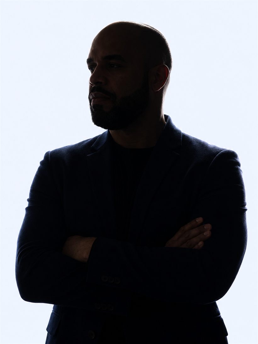 Professor Rogério de Oliveira em contraluz, de braços cruzados